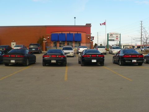 1993 Ford Probe - Several 1993 Ford Probe cars are parked in a lot outside a brick building.