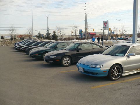1993 Ford Probe - A line of Mazda MX-6s are parked in a lot, with a silver model in the foreground blue lower body trim.