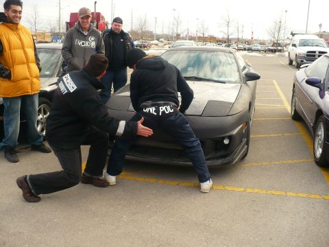 1993 Ford Probe - Several people are gathered around the front of a 1993 Ford Probe in a parking lot.