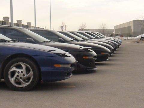 1993 Ford Probe - A row of 1993 Ford Probes are parked in a lot under an overcast sky.
