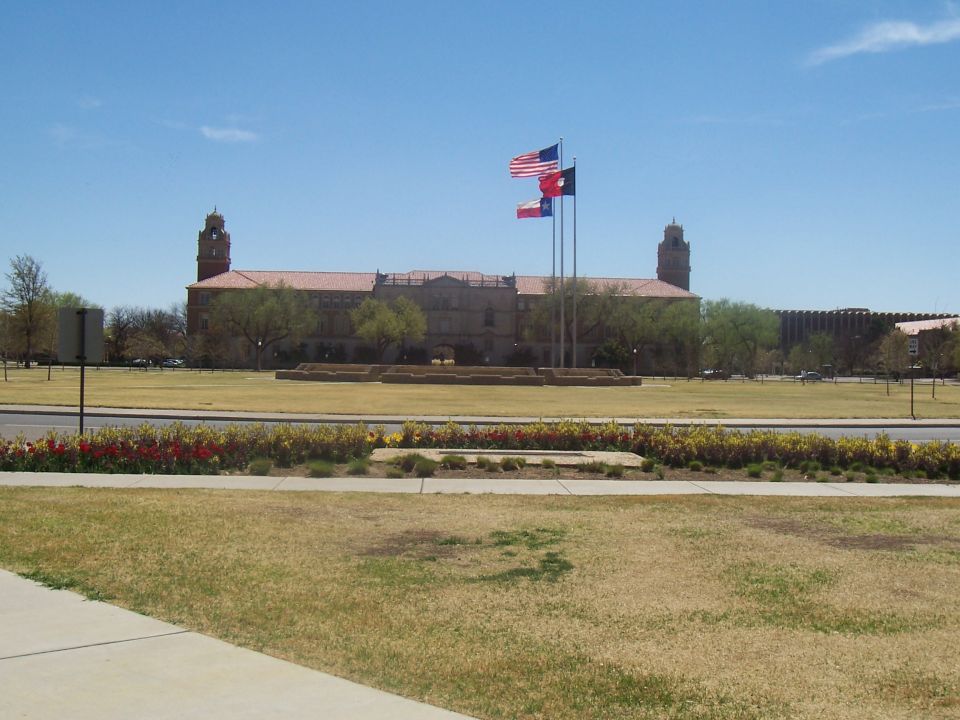 Campus buildings with flags flying under a blue sky