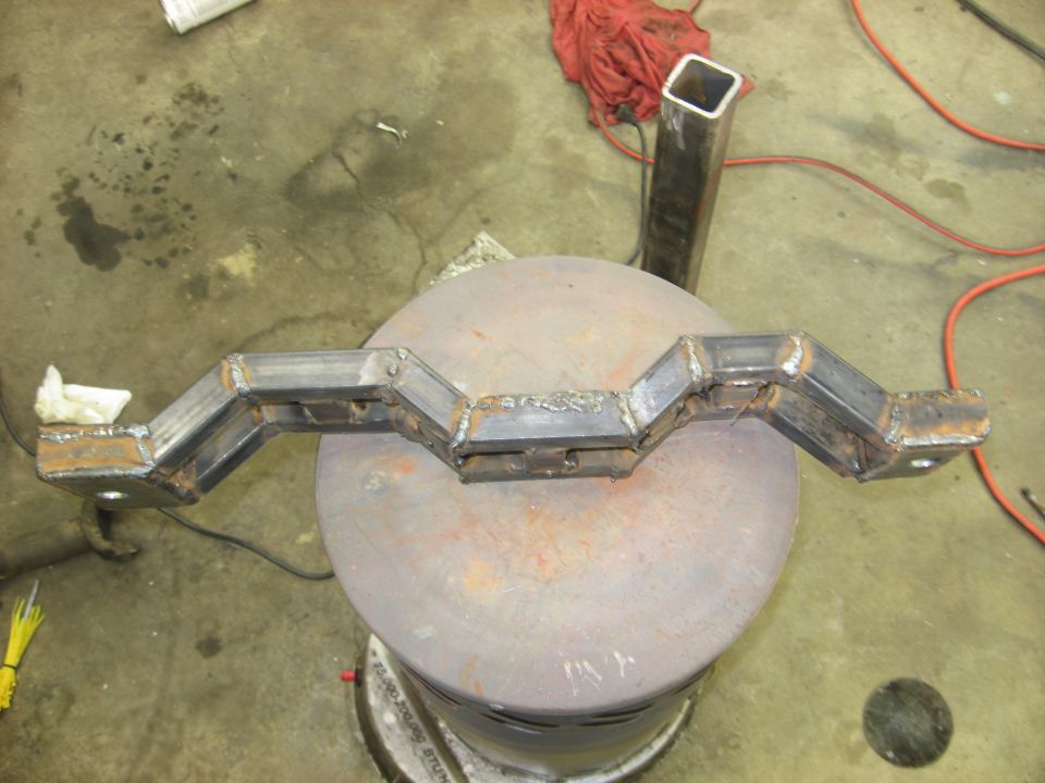 Fabricated metal part with zigzag shape, resting on a round metal surface