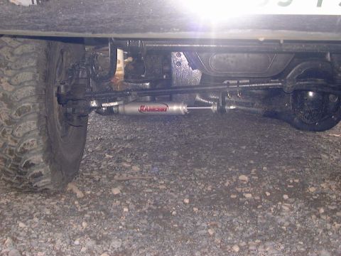 1994 Ford Bronco - Close-up of a Rancho steering stabilizer mounted on the front axle of a vehicle.