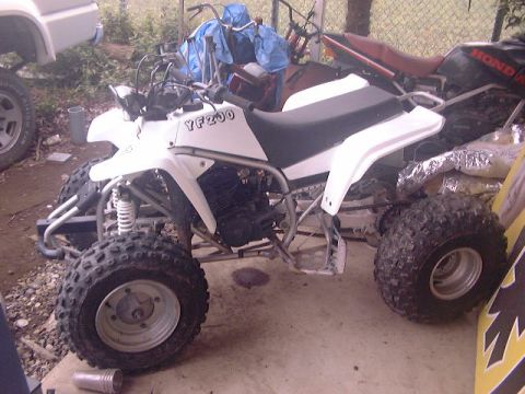 1994 Ford Bronco - A white ATV with 'YF200' visible is parked in a cluttered area with other vehicles.