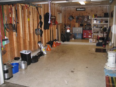 1995 Ford Bronco - A motorcycle is parked in a cluttered garage next to various tools and storage units.