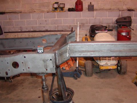 1991 Ford Bronco - Working on vehicle frame with a digital level. Background shows a lawn mower and tools.