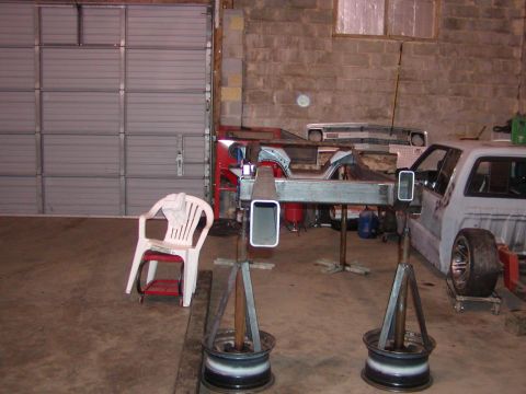 1991 Ford Bronco - A workshop scene shows a truck frame undergoing repair, with other vehicle parts visible.