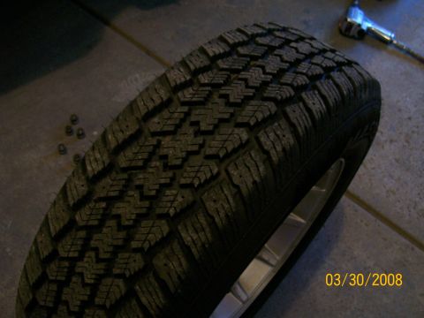 1995 Mercury Grand Marquis - A tire and wheel assembly is shown, with lug nuts on the floor next to it.