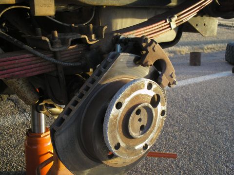 1990 Ford Bronco - Vehicle brake rotor and suspension components are visible, with a jack supporting the frame.