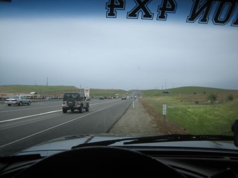 1995 Ford Bronco - A Jeep Wrangler is seen from behind on a highway, with other vehicles in the distance.