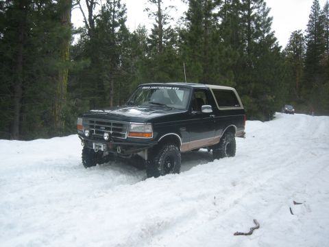 1995 Ford Bronco - A 1995 Ford Bronco navigates a snowy trail through a forest.