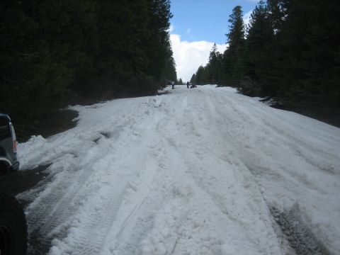1995 Ford Bronco - A snowy mountain road with tire tracks and distant figures suggests a challenging drive.