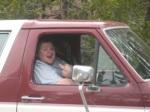 1995 Ford Bronco - A driver in a maroon and white SUV gives the middle finger to the camera while a passenger sits behind them.