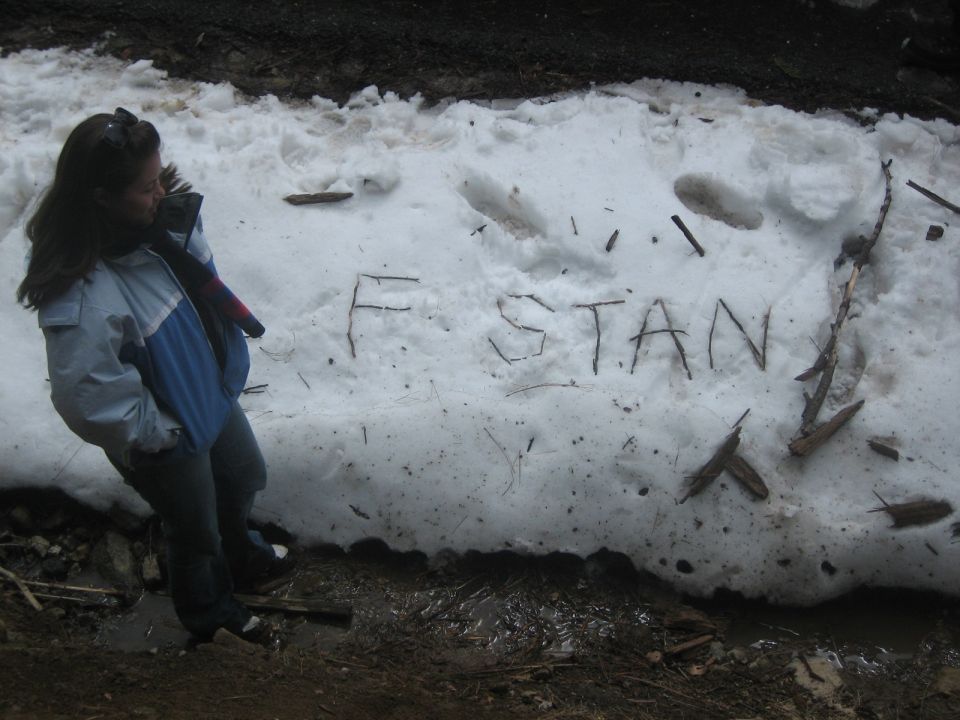 Person stands by snow with 'F STAN' written in it using sticks