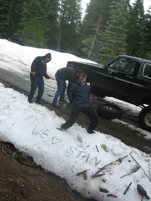 1995 Ford Bronco - Three people are gathered around a black SUV with a removed tire in the snow. 'WE