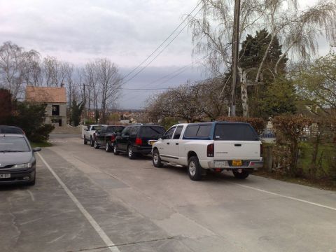1991 Ford Crown Victoria - A line of vehicles, including trucks and SUVs, are parked in an outdoor lot under an overcast sky.