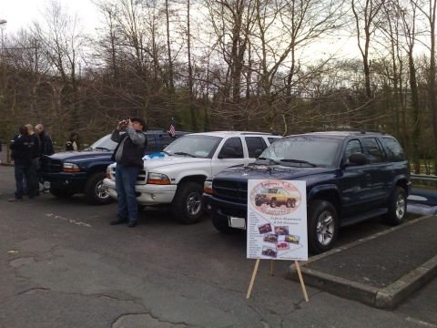 1991 Ford Crown Victoria - Several SUVs are parked in a lot, with a sign displaying vehicle photos and text in front of one.