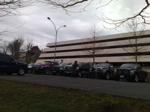 1991 Ford Crown Victoria - A line of pickup trucks are parked in a lot under a cloudy sky.