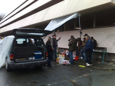 1991 Ford Crown Victoria - People are gathered around an open van and a grill, possibly for an outdoor event.