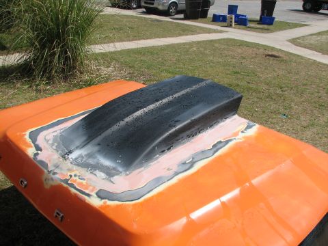 1979 Ford Bronco - An orange hood lying on a suburban front lawn with a black cowl scoop bonded in and the surrounding seam mid-bodywork, showing wet-sanded b…