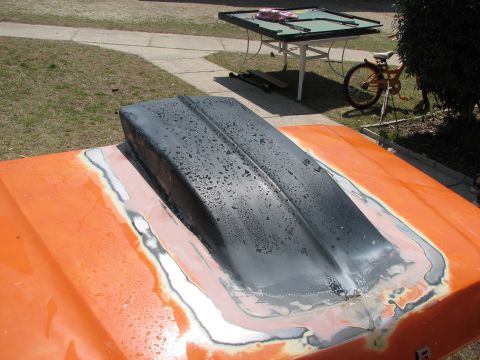 1979 Ford Bronco - gray cowl-style hood scoop freshly bonded and sanded onto an orange-painted truck hood drying outdoors.