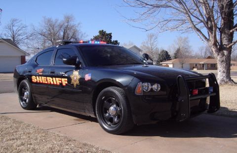 1998 Ford Crown Victoria - A black sheriff's car with a push bar and light bar is parked on a driveway.