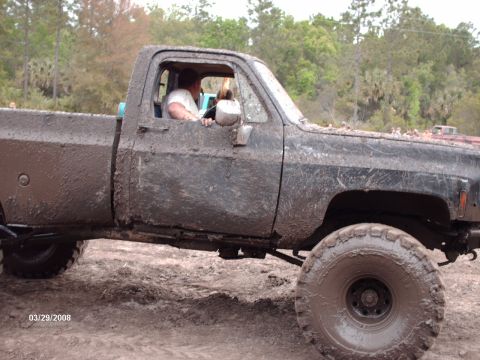 1982 Ford F-100 - Pickup truck covered in mud, seen from the side with a driver inside. Date stamp 03/29/2008.