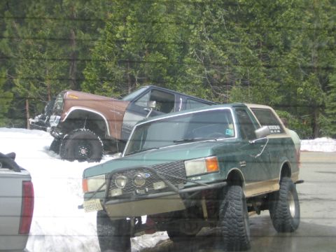 1989 Ford Bronco - A modified green 1987 Ford Bronco is parked on a snowy roadside, with another brown SUV behind it.