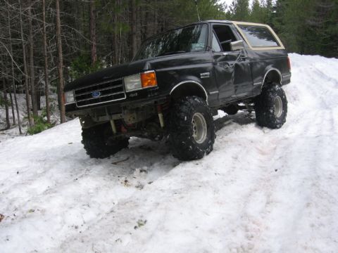 1989 Ford Bronco - A modified Ford Bronco navigates a snowy incline, its off-road capabilities.