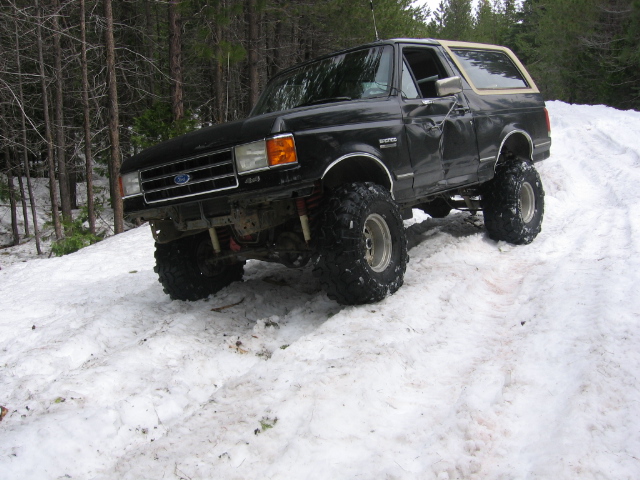 Black Ford Bronco with lifted suspension and large tires on a snowy hill