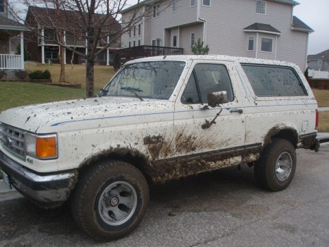 1987 Ford Bronco - This 1987 Ford Bronco is heavily covered in mud, suggesting recent off-road use.