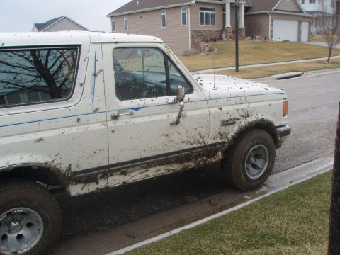 1987 Ford Bronco - Muddy 1987 Ford Bronco parked on the side of the road after off-roading.