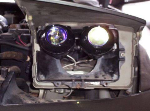 1995 Ford Probe - The vehicle's headlight housing is open, revealing aftermarket projector lights.