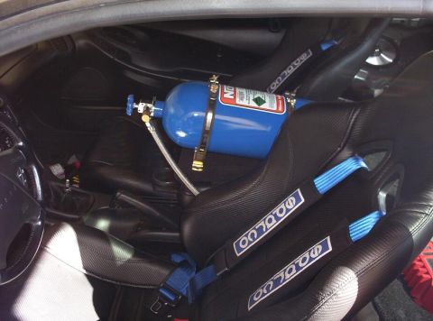 1995 Ford Probe - A blue nitrous oxide tank is installed in the passenger seat area of a car, alongside racing seats.