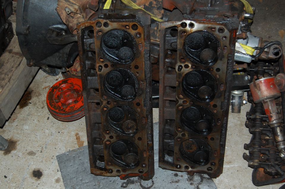 Two dirty engine cylinder heads with visible valves and combustion chambers