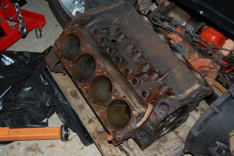 1994 Ford Bronco - A V8 engine block sits on wooden planks, surrounded by garage items and shop equipment.