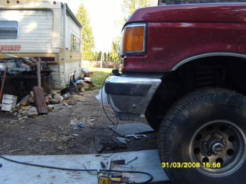 1989 Ford Bronco - Close-up of a red Ford truck's front end, with an RV parked nearby.