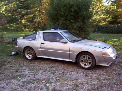 1995 Ford Probe - A silver sports coupe with a distinctive angular design sits parked outdoors on a gravel surface.