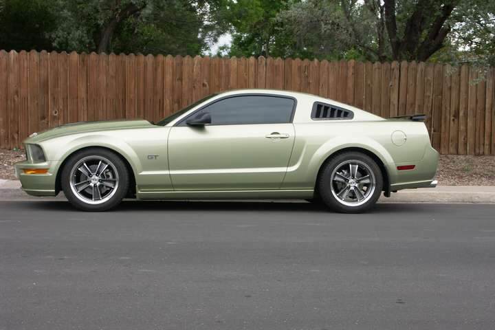 Side view of a light green coupe with a GT badge and tinted windows