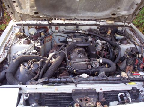 1995 Ford Probe - The engine compartment of a vehicle is shown with the hood open, revealing various mechanical parts and wiring.