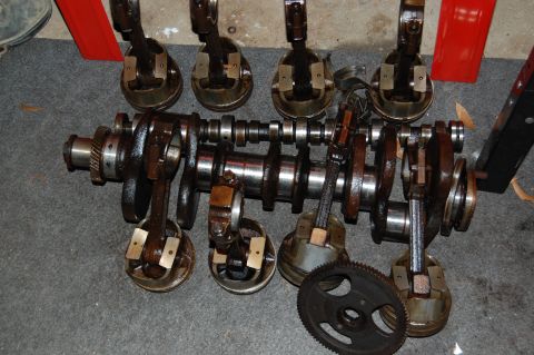 1994 Ford Bronco - Engine crankshaft and pistons are laid out on a gray surface, with a gear nearby.