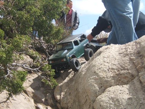 1988 Ford Bronco - RC Bronco navigates a challenging rocky terrain, with onlookers observing the climb.