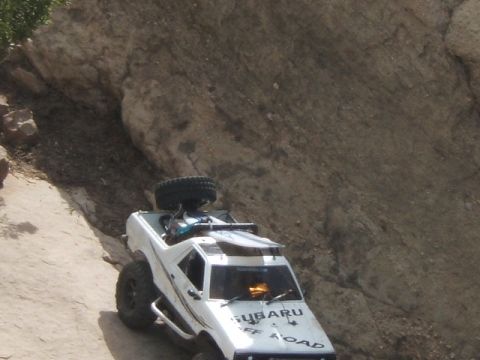 1988 Ford Bronco - A modified Subaru vehicle navigates a challenging off-road trail with steep, rocky terrain.