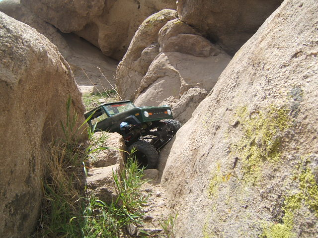 Green 1988 Ford Bronco RC rock crawler navigating a narrow rocky path
