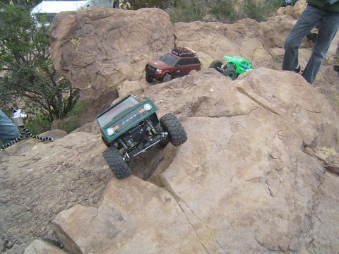 1988 Ford Bronco - Multiple remote control rock crawlers navigate a challenging rocky terrain.