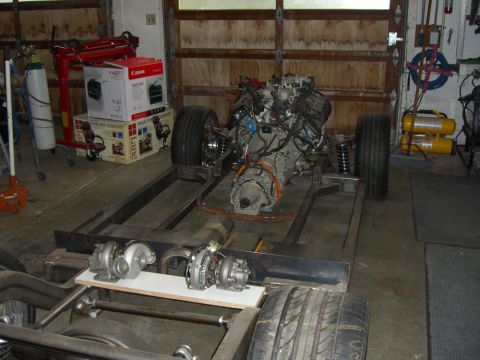 1964 Ford Ranchero - Engine and chassis components are laid out in a garage, with turbochargers visible on a plank.
