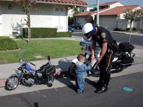 1989 Ford Bronco - A police officer on a motorcycle interacts with a child on a sidewalk.