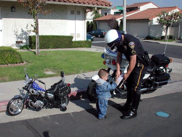 Police officer writing a ticket to a child next to a motorcycle