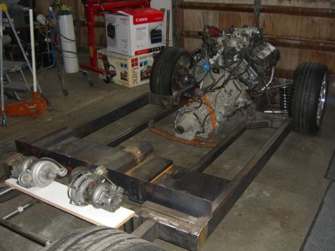 1964 Ford Ranchero - Custom chassis build with engine, transmission, and turbochargers in a garage setting.