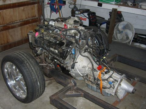 1964 Ford Ranchero - This is an engine and transmission assembly mounted on a custom metal frame, with one wheel attached.